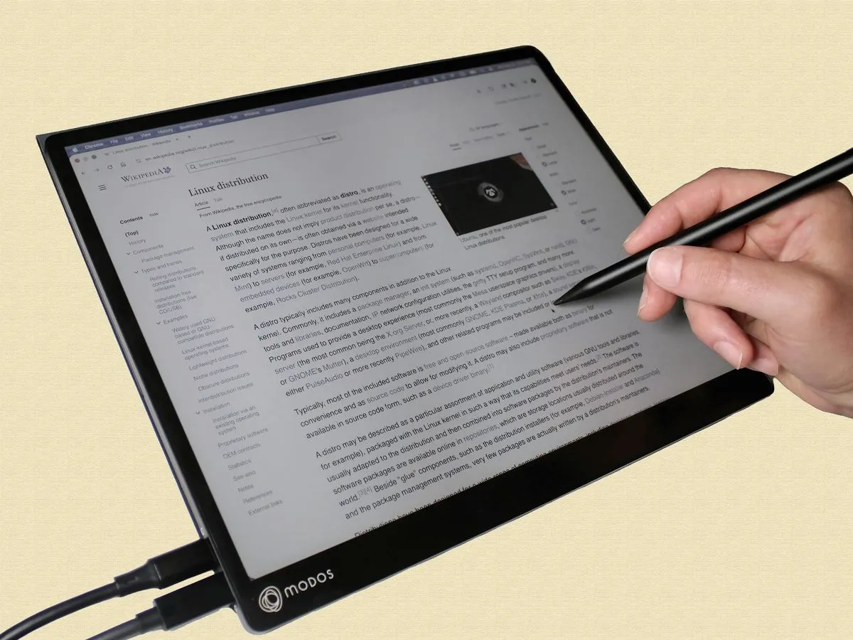 Close-up of a hand using a stylus on an e-paper PC monitor.