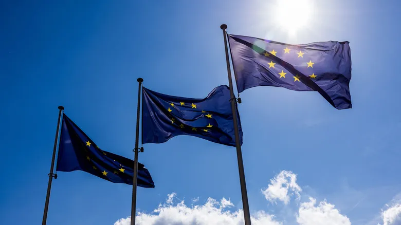 Photo of three European Commission flags waving on a sunny day