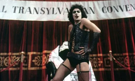 Curry in heavy makeup, a black basque, stockings and suspenders.